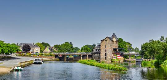 Picturesque view of Messac with a river weir and traditional town buildings lining the waterfront.