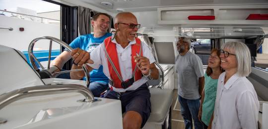 Inside a boat, a Le Boat team member gives a pre-departure briefing to four customers.