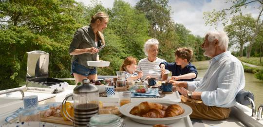 Family on the deck of the boat having breakfast