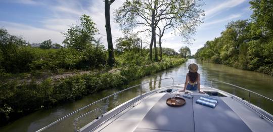 Tranquil view from the boat as a woman lounges under blue skies on a scenic houseboat.