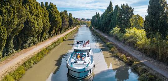 A canal boat cruises the scenic Canal du Midi along the Canal du Midi, offering a relaxing way to explore southern France.