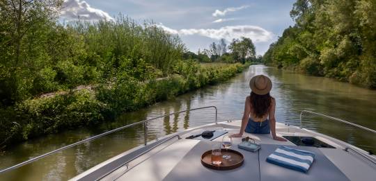 Frau sitz vorne auf dem Boot und genießt die Sonne