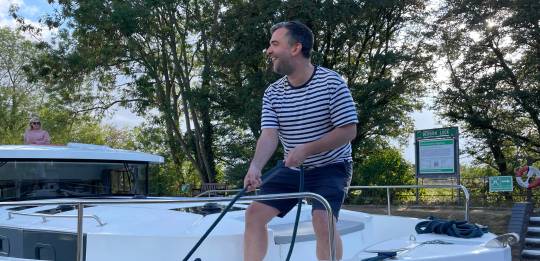 Man handling a rope on the Horizon boat’s deck while preparing to moor at a lock.
