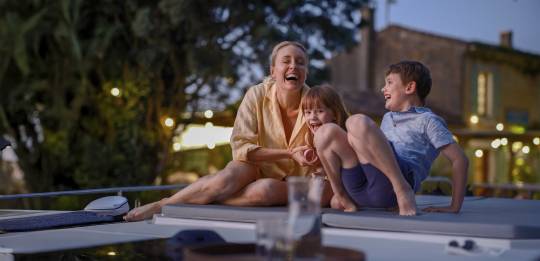 Mother and children laughing together on the boat during a warm, relaxed evening stopover.