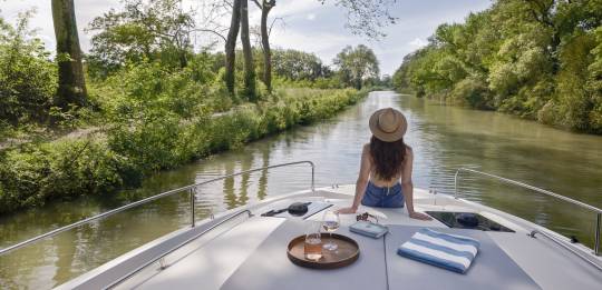 Serene solo moment at the bow of the boat as a woman admires the tree-lined river ahead.