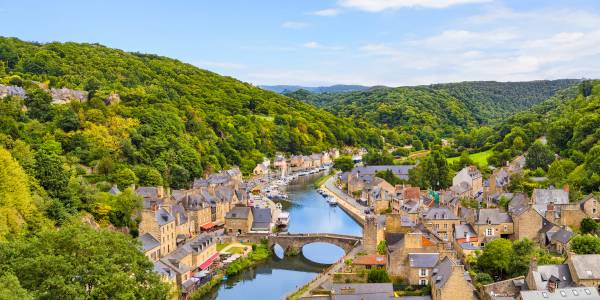 Città storica di Dinan lungo il fiume, con edifici in pietra, colline e natura.