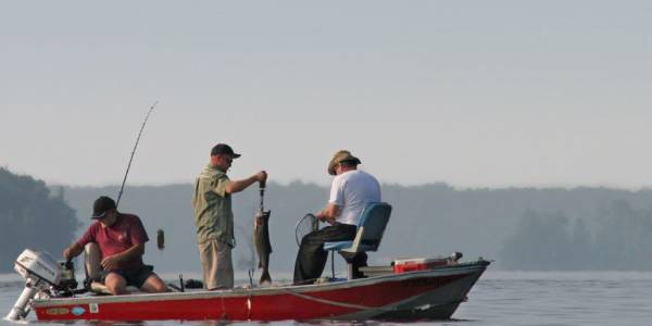 Tres hombres pescan desde un barco