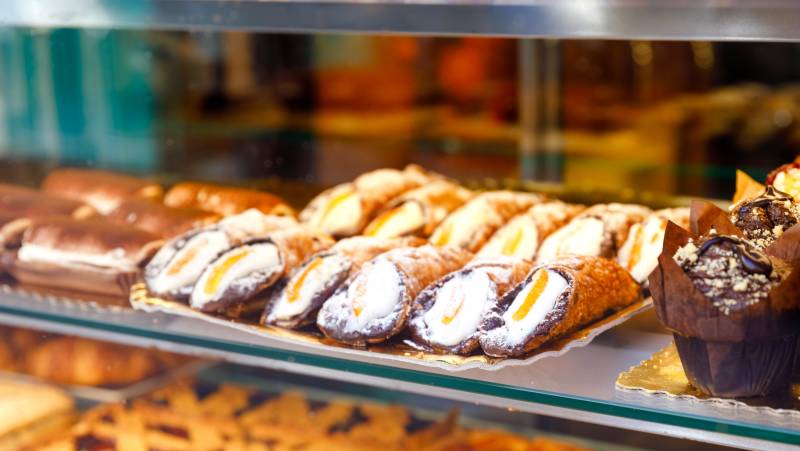 Sweet homemade cannoli stuffed with ricotta cheese cream and pistachial Sicilian dessert at market in Italy