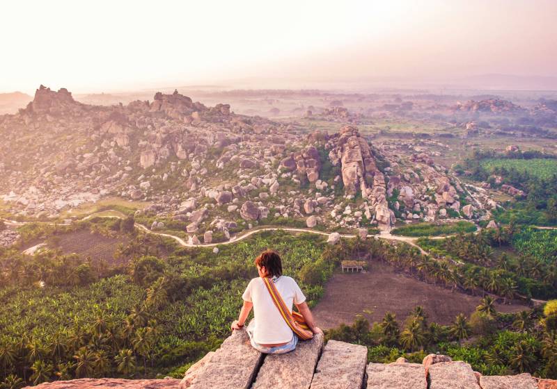 A person sitting on a rock overlooking a valley Hampi south India