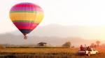 Enchanting Travels Laos Tours Hot air balloon flying over cornfield, landscape with cottage, Vang Vieng, Laos.