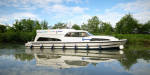 Mystique boat cruising along a calm canal surrounded by vibrant greenery.