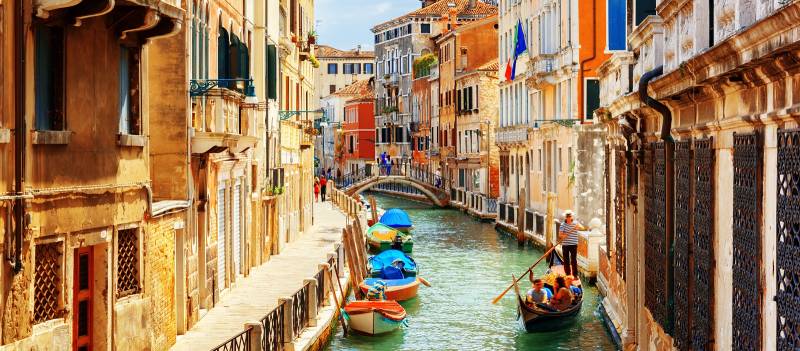Enchanting Travels Rio Marin Canal with boats and gondolas from the Ponte de la Bergami in Venice, Italy.