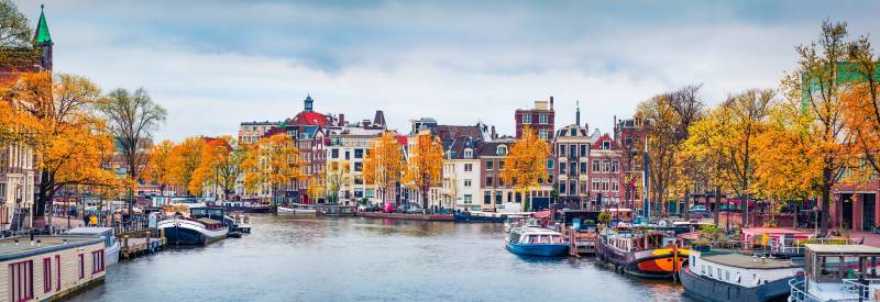 Panoramic autumn view of Amsterdam city. Famous Dutch channels and great cityscape. Gloomy morning scene of Netherlands, Europe. Traveling concept background. European Cities tours