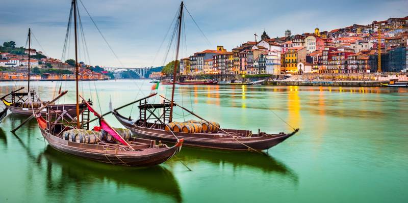Porto, Portugal old town cityscape on the Douro River with traditional Rabelo boats.