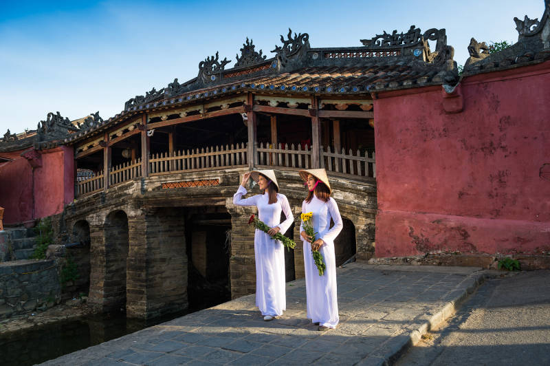 Two Vietnamese Woman standing in front of a bridge
