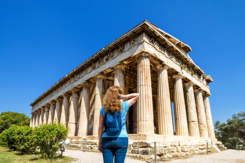 Greece Private Trip:Young woman looks at Temple of Hephaestus, Athens, Greece. This ancient Greek structure is one of main landmarks of Athens.