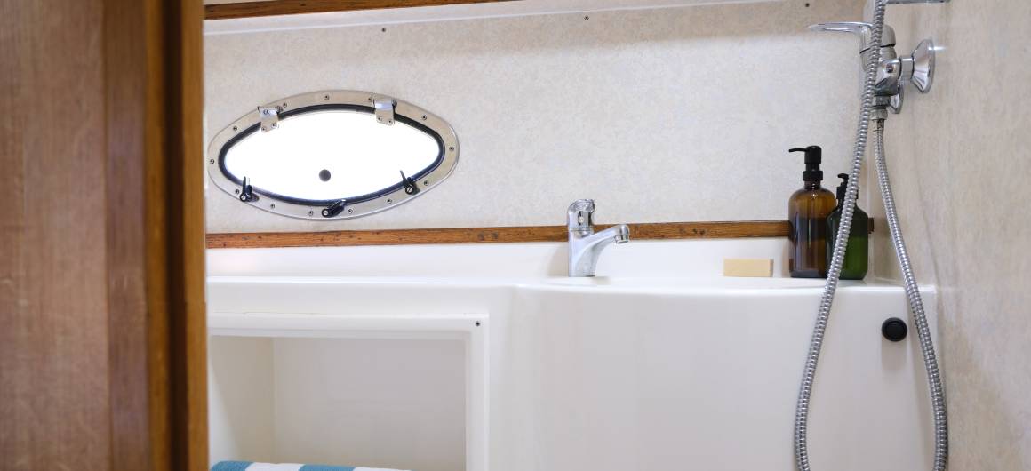 Compact bathroom on the Countess boat with a white sink, soap dispensers, and a window for natural light.