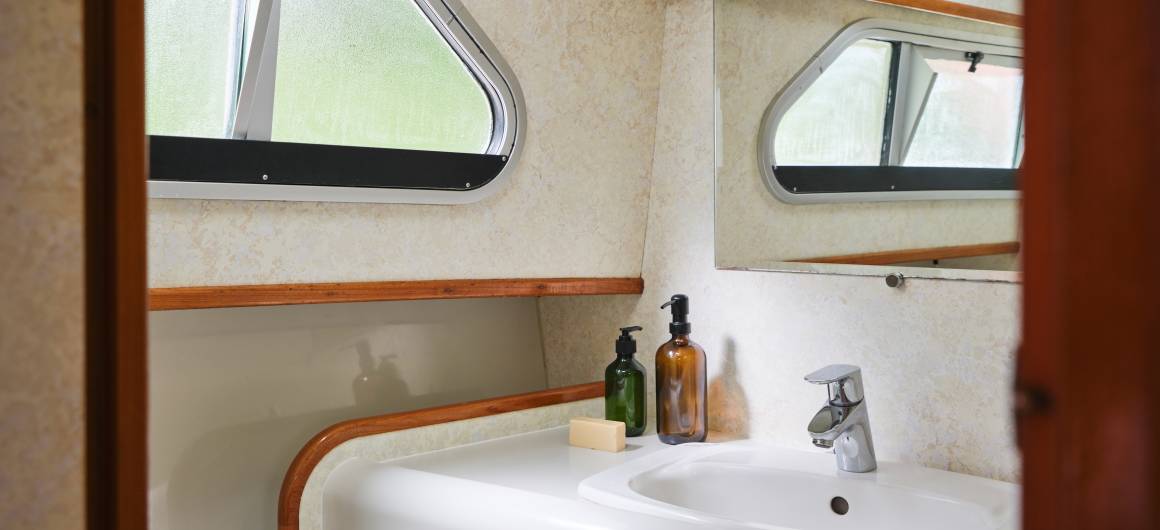 Private onboard bathroom with sink, toiletries and elegant wooden accents.