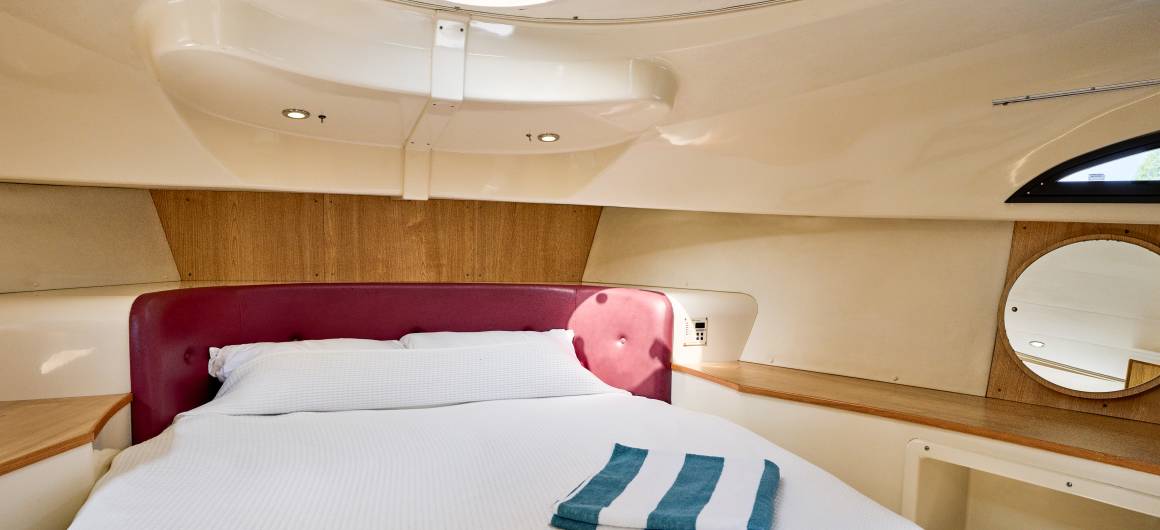 Cosy double bed with natural light from overhead hatches aboard the Royal Mystique.