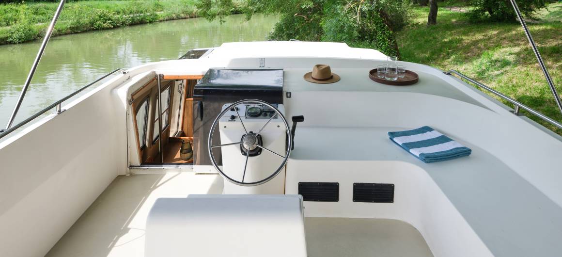 View of Royal Classique’s deck with steering controls and relaxing seating.