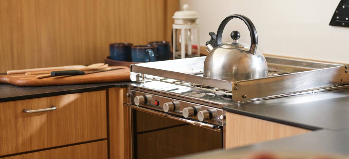 Well-equipped galley with stainless steel stove, kettle, and wooden cabinetry onboard.