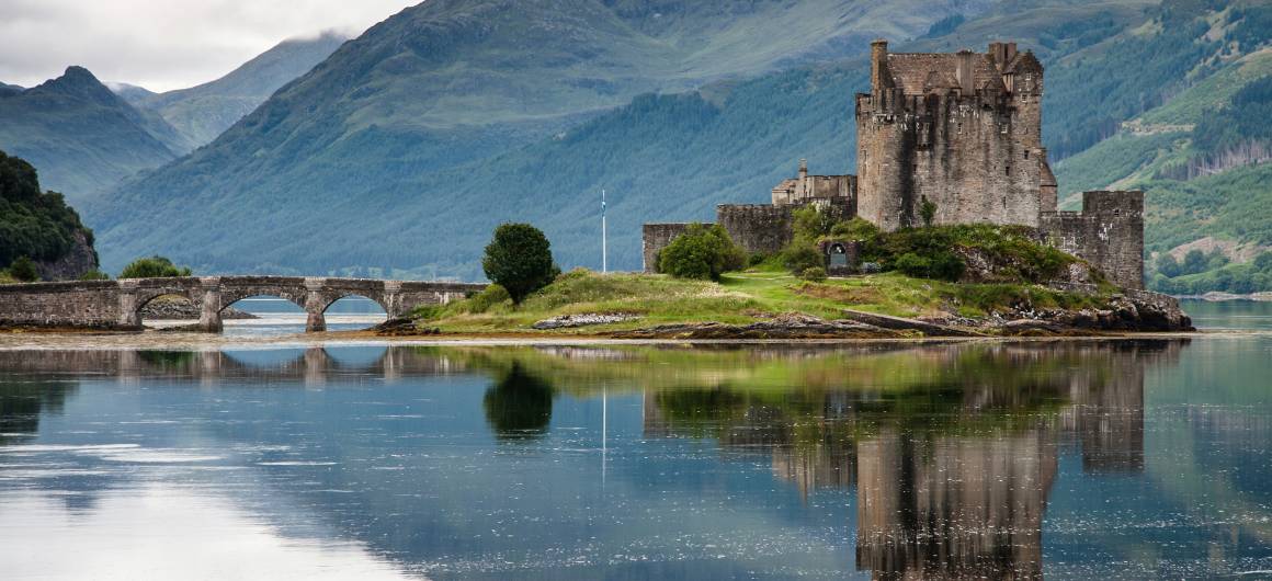 Eilean Donan Castle liegt auf einer kleinen Gezeiteninsel, wo drei Meereslochs zusammentreffen, mit einer Steinbrücke und Bergkulisse.
