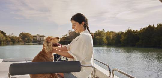 Woman sitting on the bench seat on the top deck of a Horizon boat with a tan cocker spaniel dog.