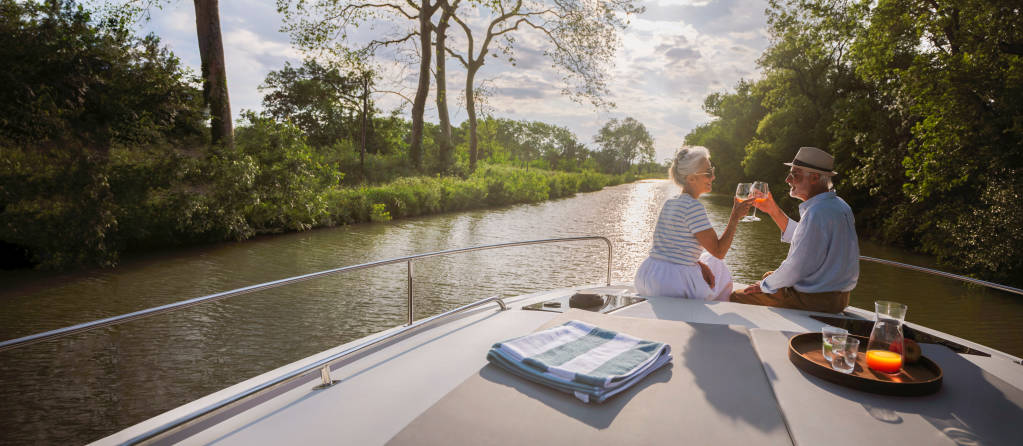 Romantic sunset moment for a couple enjoying drinks at the front of their boat on a peaceful canal.