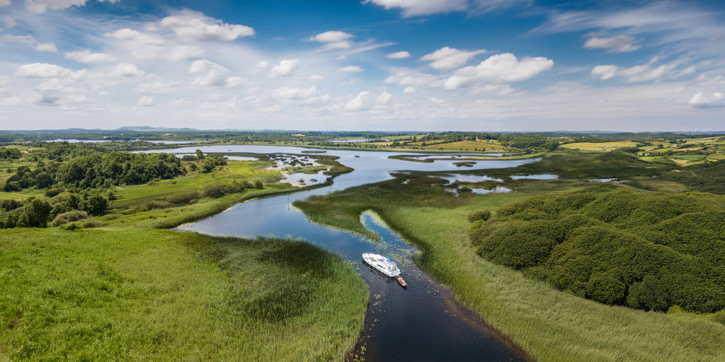 Veduta aerea di una barca bianca che naviga tra le paludi tortuose del fiume Shannon.