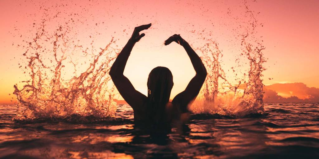 Woman splashing in the water at sunset in the Exumas