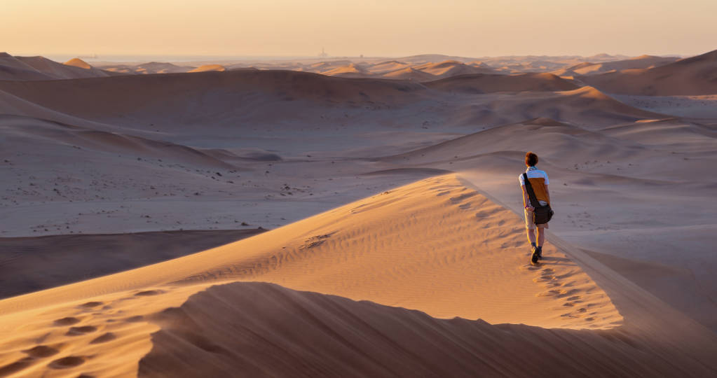 Tourist walking on the scenic dunes of Sossusvlei, Namib desert, Namib Naukluft National Park, Namibia, Africa