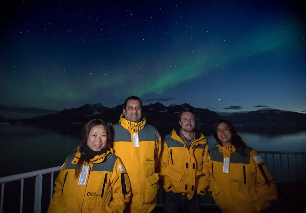 A group of Quark Expeditions guests bask in the glow of the Northern Lights.