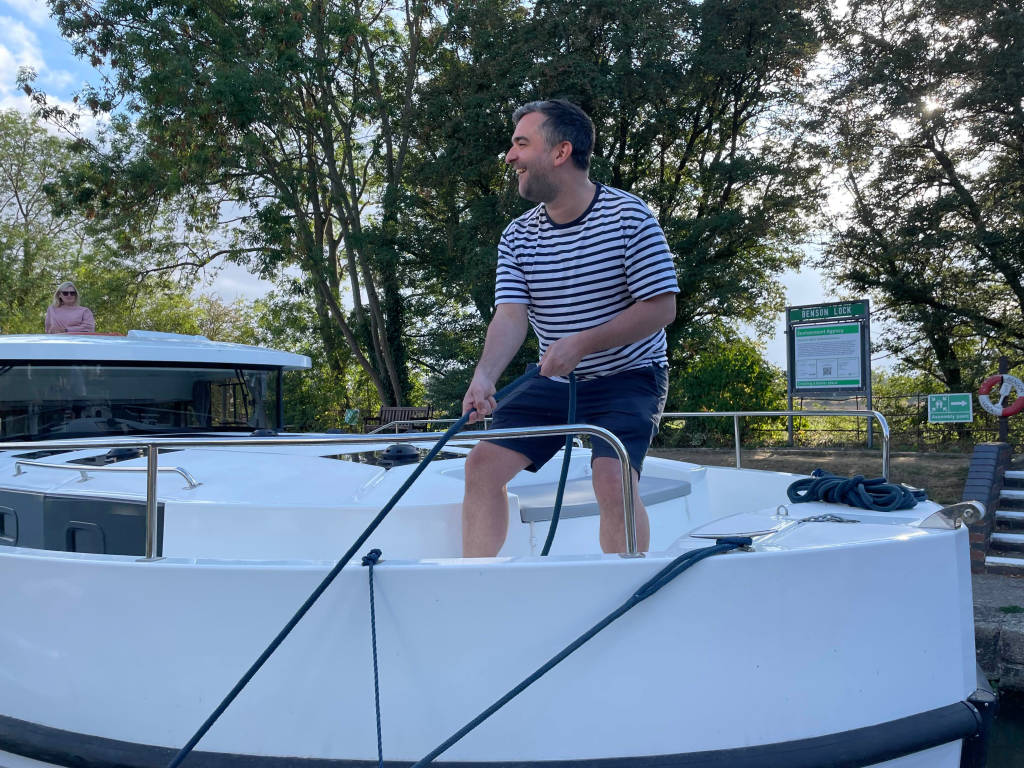 Man handling a rope on the Horizon boat’s deck while preparing to moor at a lock.