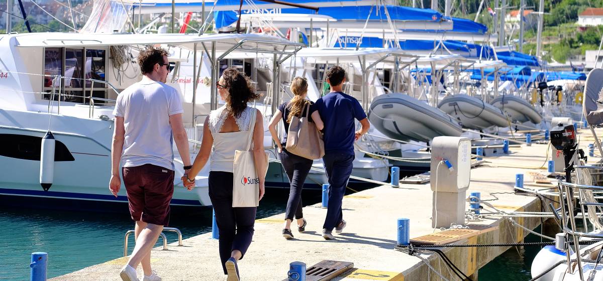 Couples walking along a jetty next to yachts