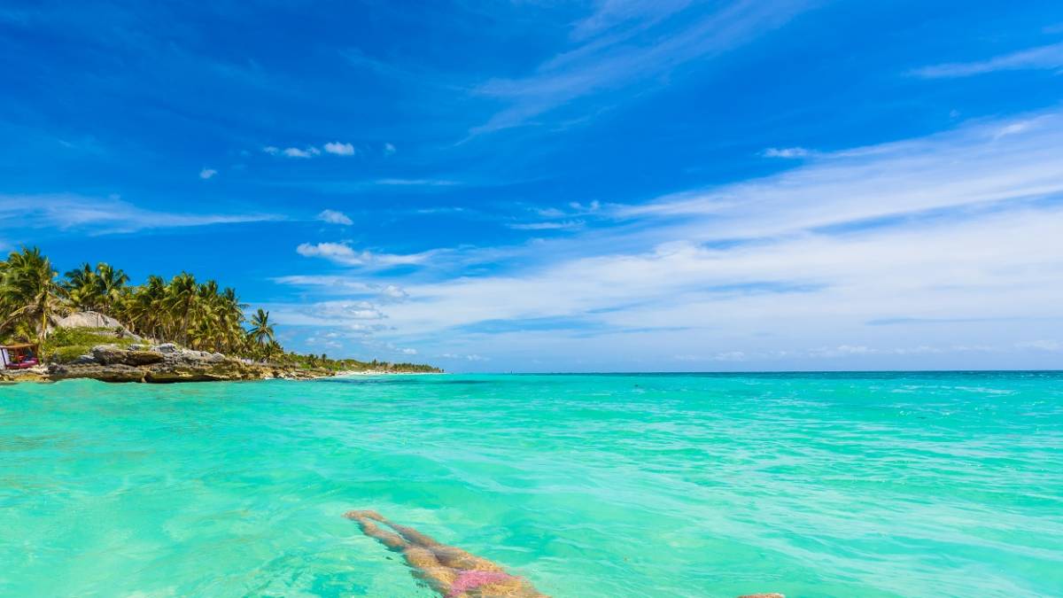 Enchanting Travels Mexico Tours relaxing in turquoise waters of Caribbean Sea in front of paradise beach in Tulum