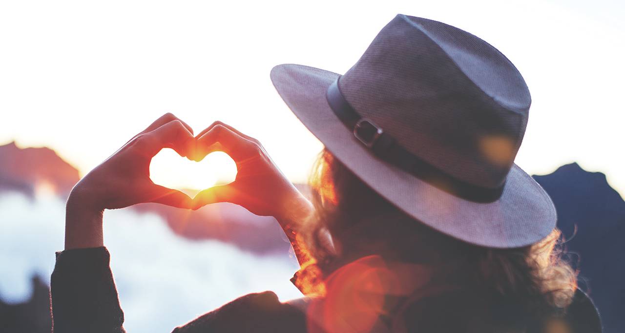 Hands making a heart in front of the sunset