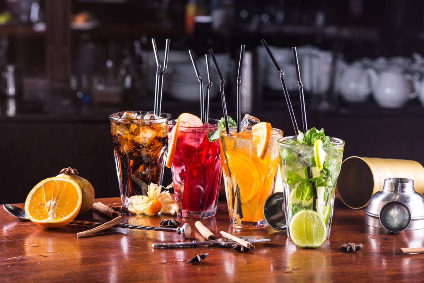 four colorful cocktails on table with ingredients