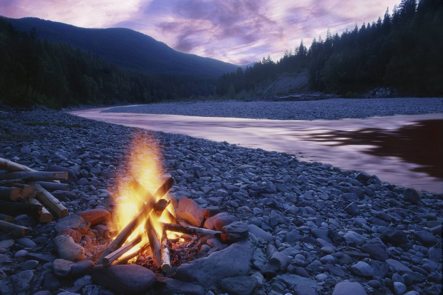 campfire next to river at dusk