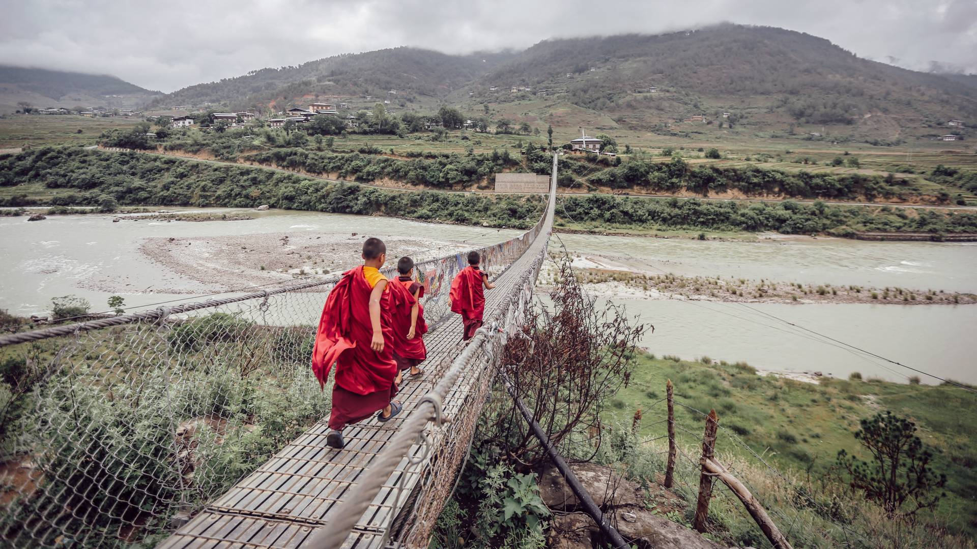 Monks walking over a bridge in Bhutan, Asia