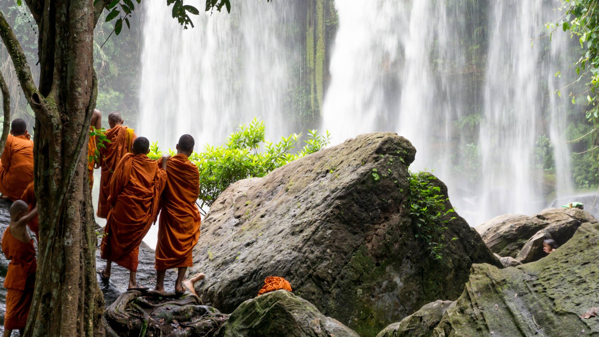 Group of young buddhist monks enjoying the view of Kulen Waterfall in Cambodia, Asia