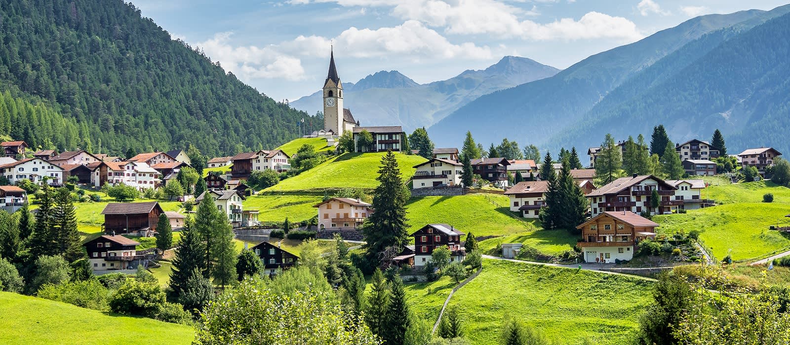 Graubuenden, Switzerland with view of houses on green grassy hills