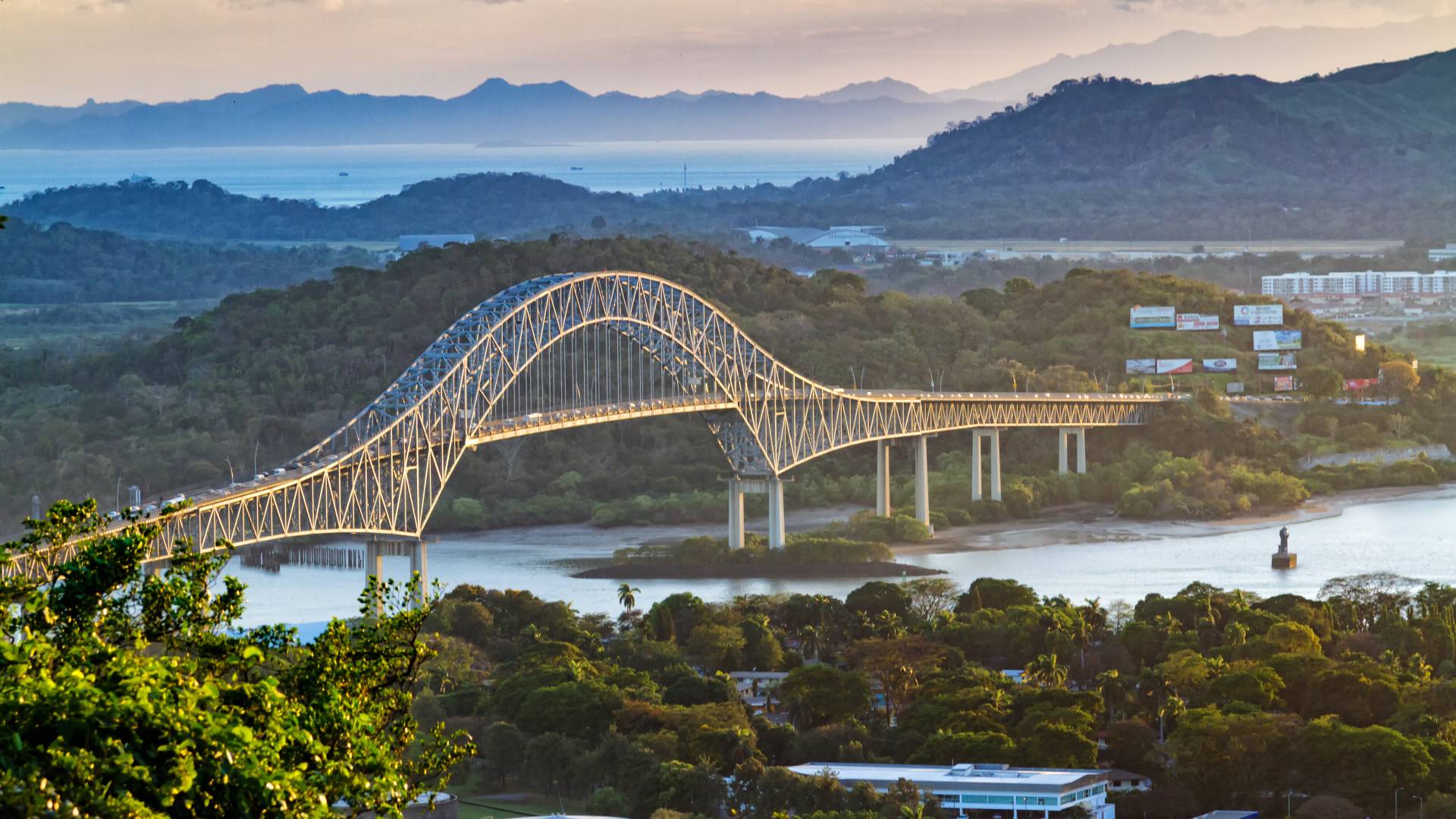 Panoramic aerial view of the Bridge of The Americas over the Panama Canal Pacific Entrance. Sunset scene with a gentle mist in the background. The bridge is spanning two continents - two Americas.