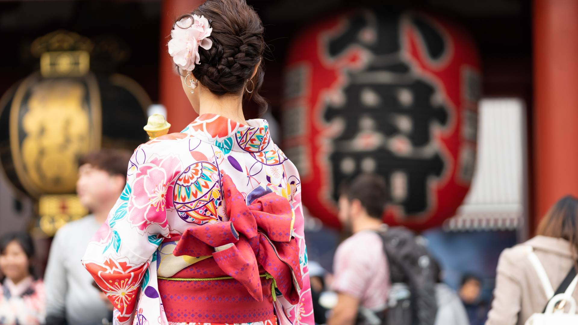 Junge Frau im Kimono mit dem Sensoji Tempel in Tokio im Hintergrund