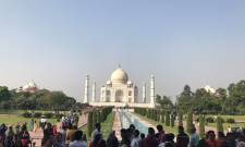 a group of people standing in front of a crowd with Taj Mahal in the background