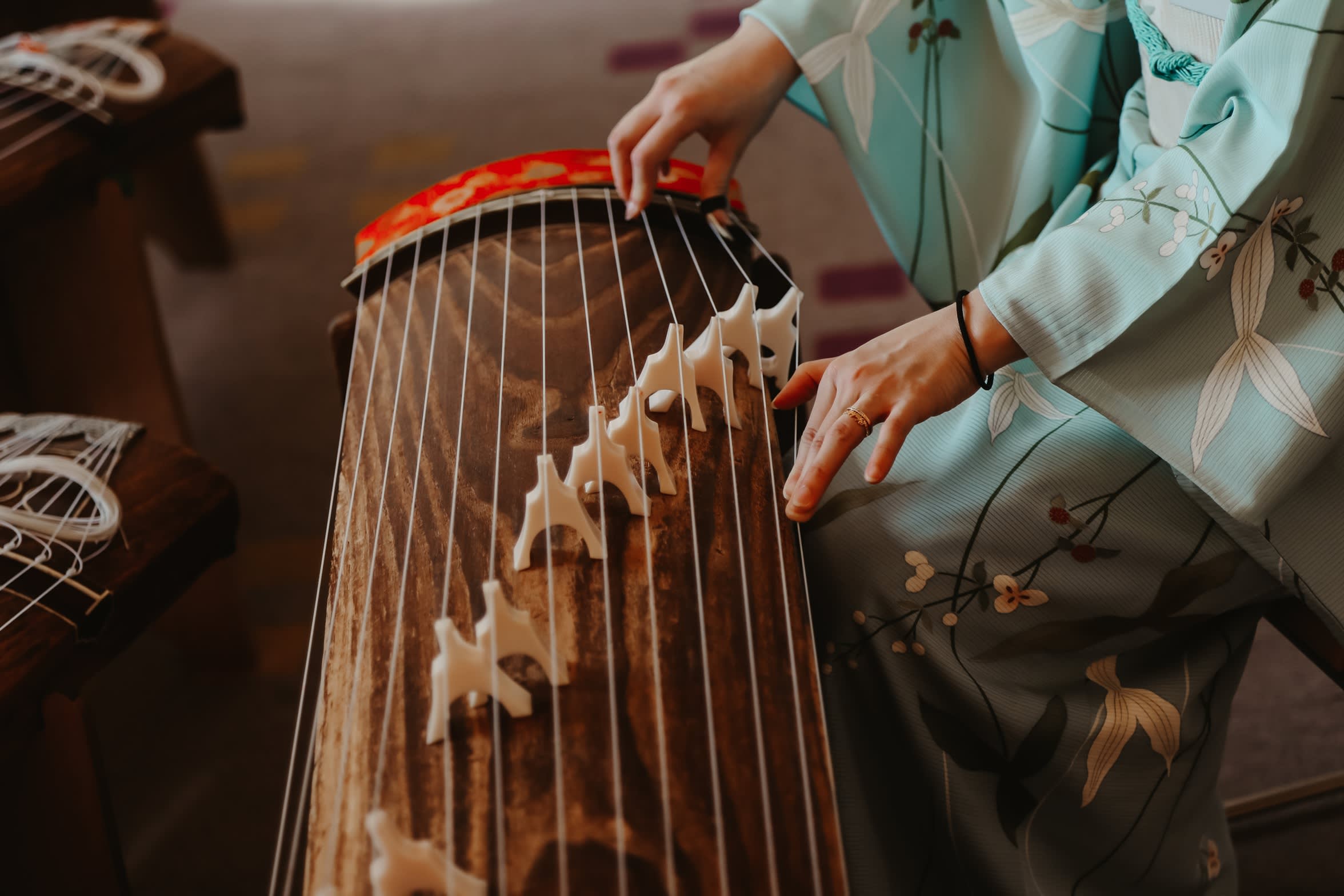 Eine Frau in einem Kimono spielt auf einer traditionellen japanischen Harfe, der Koto.