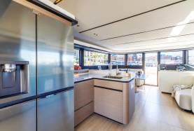 Moorings 534PC galley with a full-size refrigerator and sink, opening to the saloon and helm beyond.
