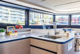 Moorings 534PC galley with an L-shaped worktop, sink, and settee seating beyond.