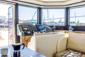 Moorings 534PC saloon helm with multifunction displays, VHF radio and compass, with a settee alongside.