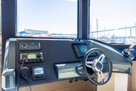 Moorings 534PC helm with Raymarine VHF, autopilot, chartplotter, Fusion audio unit, compass, and helm wheel.