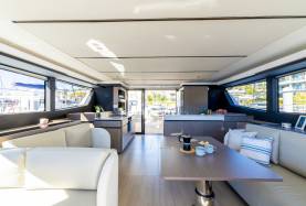 Moorings 534PC saloon with a settee, dining table, and galley with a cooktop and oven opening to the cockpit.